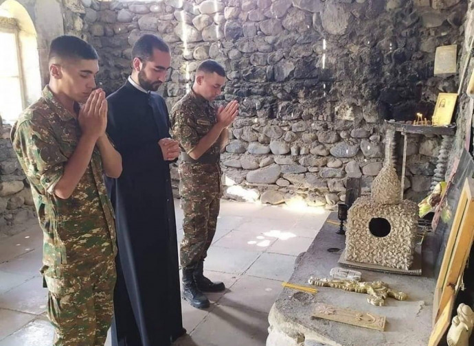 Un sacerdote prega con i soldati